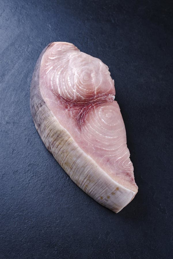 Raw swordfish steak offered as close-up on a black board with copy space. Raw swordfish steak offered as close-up on a black board with copy space