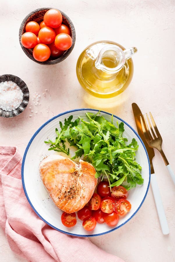 Pink tuna steak served with arugula and tomatoes. Healthy balanced meal. Pink tuna steak served with arugula and tomatoes. Healthy balanced meal