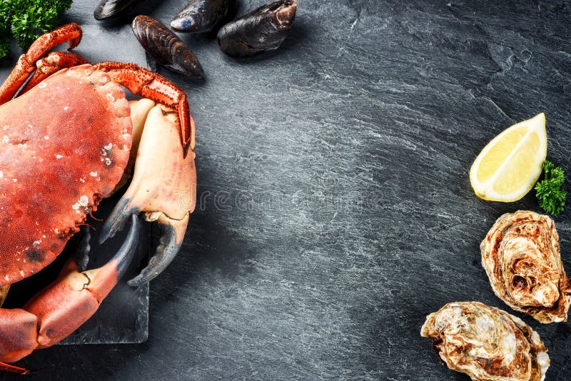 Steamed crab and fresh oysters on dark background. Sea food dinner concept with copy space