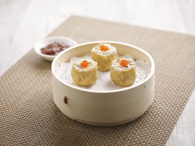 Steamed Pork Dumpling Siew Mai with chopsticks served in a dish isolated on mat side view on grey background