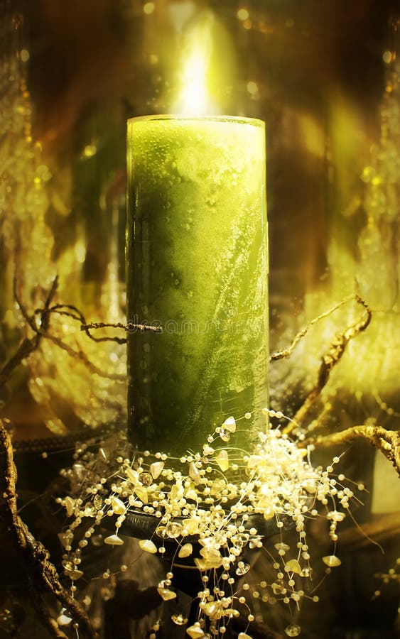 A green holiday candle with flame and branch decorations at the base. A green holiday candle with flame and branch decorations at the base.