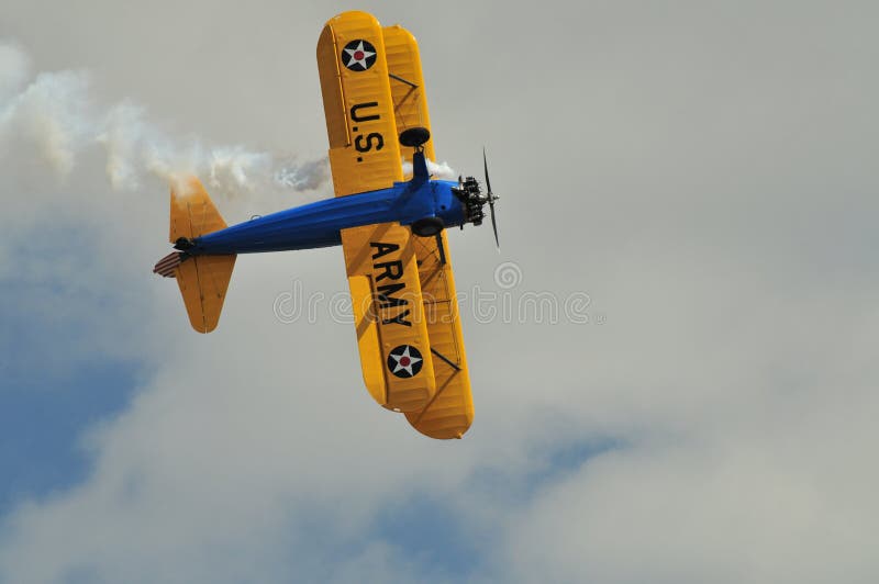 A Boeing Stearman PT-17 Kaydet is seen from directly below the aircraft with an airshow smoke trail. The aircraft is painted in US Army primary training colors from the 1930s. A Boeing Stearman PT-17 Kaydet is seen from directly below the aircraft with an airshow smoke trail. The aircraft is painted in US Army primary training colors from the 1930s.