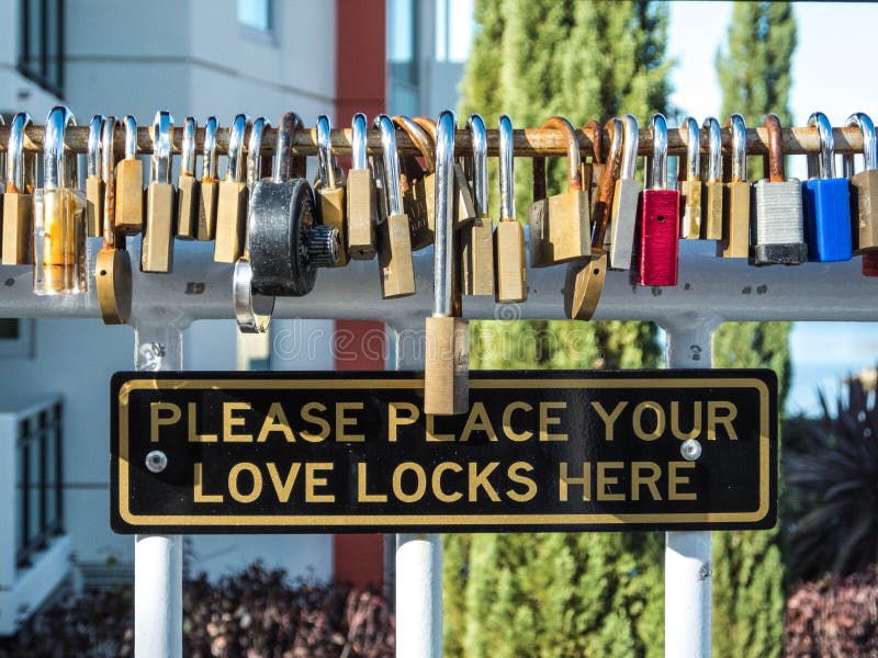 Steel Gate Adorned with Multiple Love Locks and a Cautionary Sign