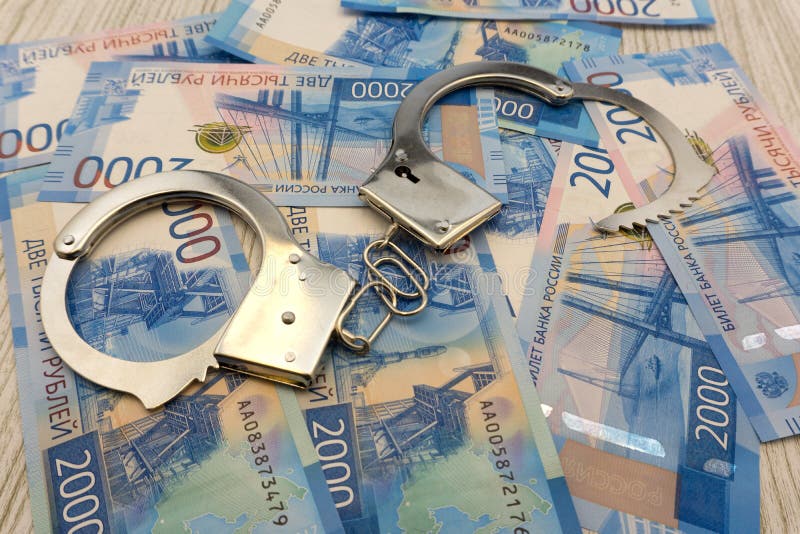 Steel police handcuffs lying on the background of dollars with folded stack of banknotes of russian roubles . royalty free stock photos Steel police handcuffs lying on the background of dollars with folded stack of banknotes of russian roubles . royalty free stock photos