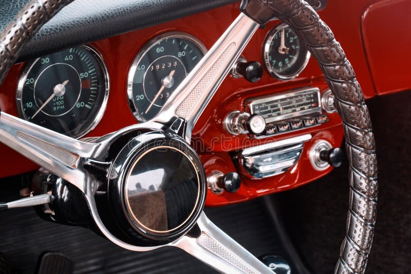 Steering wheel, speedometer, revs, clock dials, radio scale, buttons and knobs on front panel red coupe old timer sports car