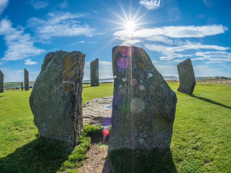 Standing Stones of Stenness is a Neolithic monument northeast of Stromness on mainland Orkney, Scotland. Part of the UNESCO World Heritage Site, the Heart of Neolithic Orkney. Fisheye, green grass, blue sky with light clouds. Standing Stones of Stenness is a Neolithic monument northeast of Stromness on mainland Orkney, Scotland. Part of the UNESCO World Heritage Site, the Heart of Neolithic Orkney. Fisheye, green grass, blue sky with light clouds.