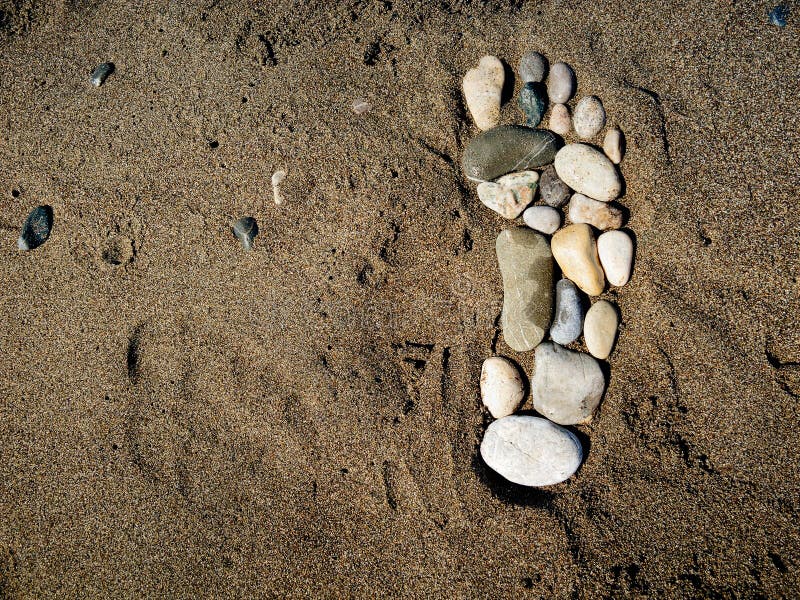 Single bigfoot footprint made of stones in the sand. Single bigfoot footprint made of stones in the sand