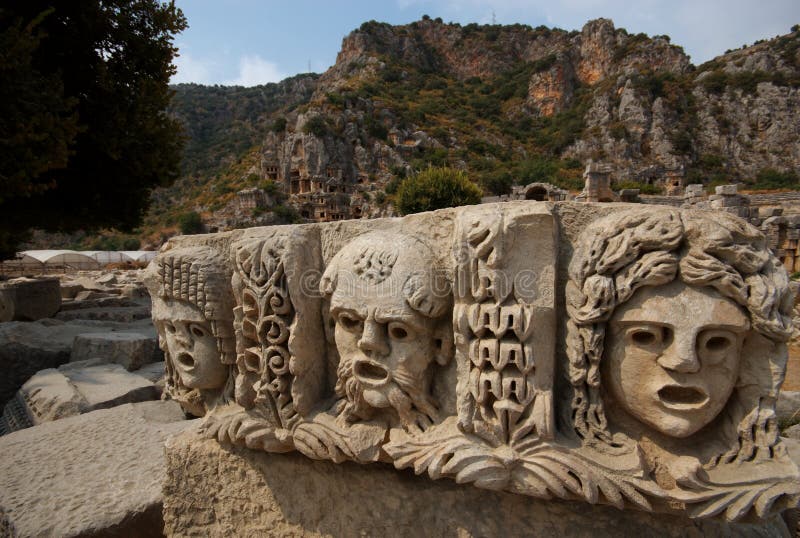A group of three dramatic masks carved into a stone platform in front of the ancient Lycian city of Myra, Turkey. A group of three dramatic masks carved into a stone platform in front of the ancient Lycian city of Myra, Turkey