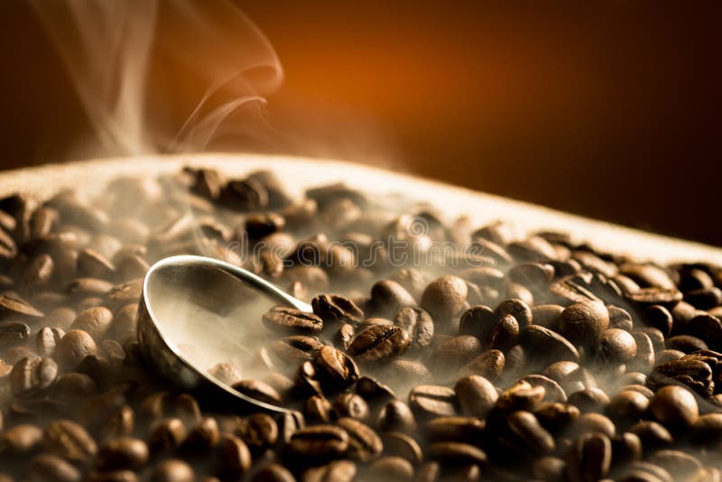 Stekheta kaffebönor med rök royaltyfri foto