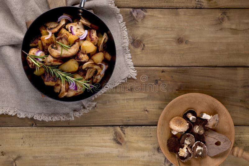 Stekte potatisar i en svart gjutjärnpanna på en träbakgrund Tappningfoto och servett i lantlig stil Fritt utrymme för text som är arkivfoton Stekte potatisar i en svart gjutjärnpanna på en träbakgrund Tappningfoto och servett i lantlig stil Fritt utrymme för text som är arkivfoton