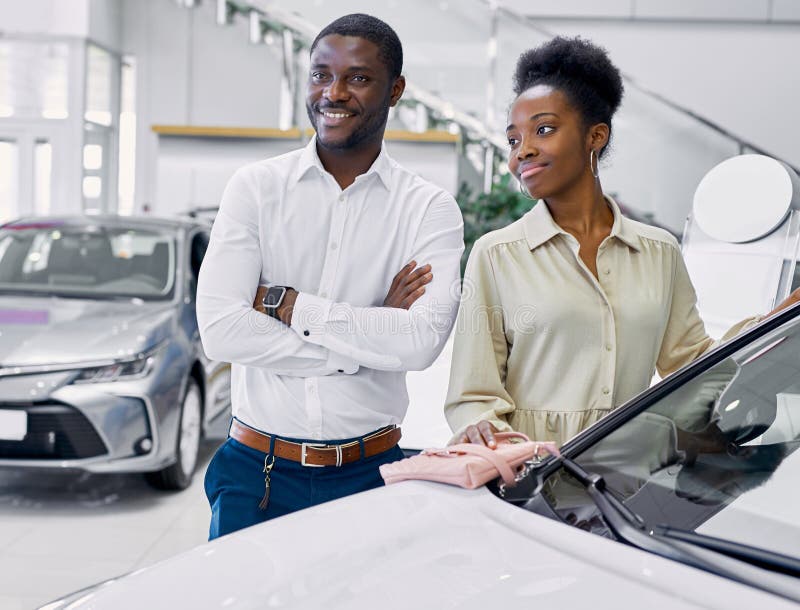 Just imagine us on the road. portrait of happy african american couple checking out a car in modern dealership, they choose new car together. Just imagine us on the road. portrait of happy african american couple checking out a car in modern dealership, they choose new car together