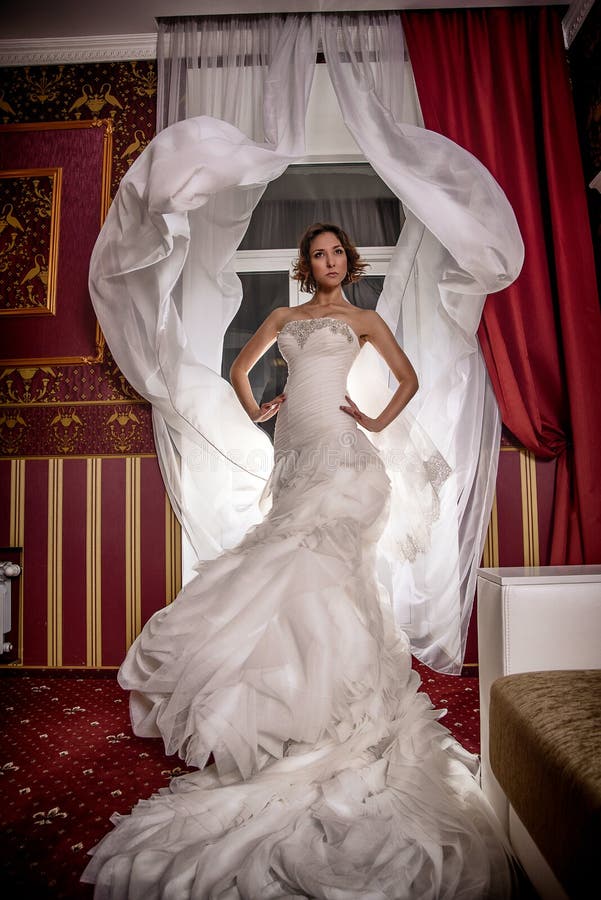 Stelt de de foto mooie bruid van de maniermode met krullend haar in een schitterende huwelijkskleding met kostbare perfect in ver stock foto's Stelt de de foto mooie bruid van de maniermode met krullend haar in een schitterende huwelijkskleding met kostbare perfect in ver stock foto's