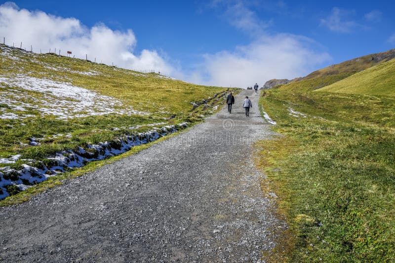 Stenen går vägen till fjällängberget med folk som fotvandrar, grönt gräs a fotografering för bildbyråer Stenen går vägen till fjällängberget med folk som fotvandrar, grönt gräs a fotografering för bildbyråer