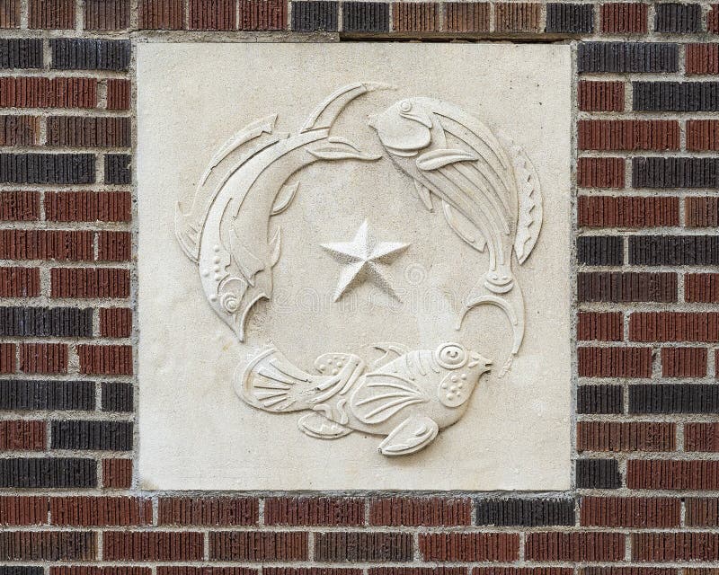 Stenhjälpspanel med tre fiskcirkling runt texaststjärnan på en byggnad i Dallas-texas i centrala staden.
