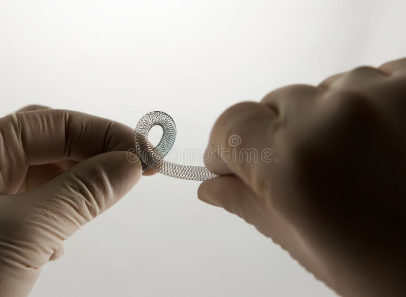 Surgeon's hands twisting self-expanding braided nitinol stent for endovascular surgery. Surgeon's hands twisting self-expanding braided nitinol stent for endovascular surgery