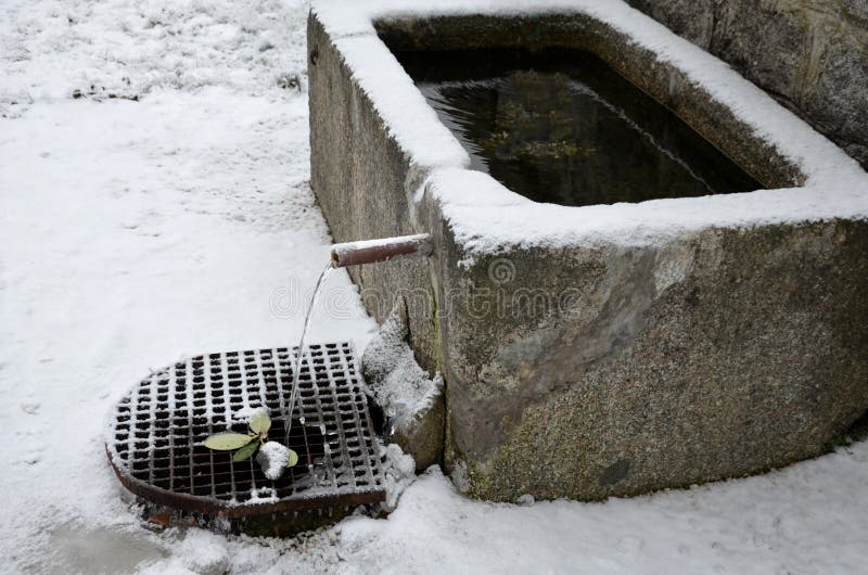 Stenvattentank tillverkad av en granitbit. Överflödet används för att fylla vattenbehållarna för att vattna blommorna på den gamla royaltyfri bild
