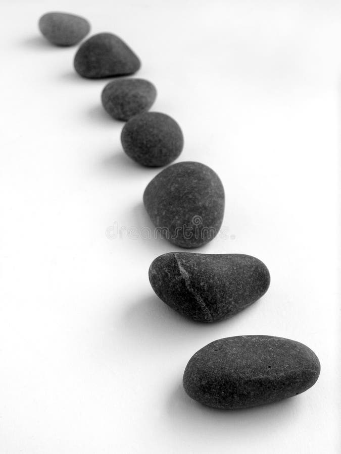 An image of a still life arrangement of dark gray stone pebbles, placed to resemble some stepping stones leading from the foreground into the distance. Concept picture of taking steps towards a goal or target. Clean white background with copyspace for text, words, etc. An image of a still life arrangement of dark gray stone pebbles, placed to resemble some stepping stones leading from the foreground into the distance. Concept picture of taking steps towards a goal or target. Clean white background with copyspace for text, words, etc.