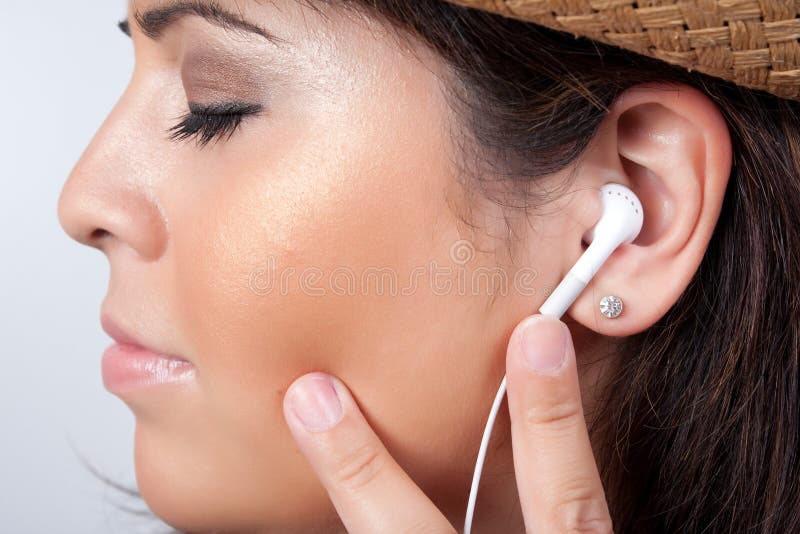 An attractive Hispanic woman listening to and getting into the music playing through her stereo earbud headphones. An attractive Hispanic woman listening to and getting into the music playing through her stereo earbud headphones.