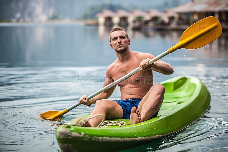 Sterke jonge mens in kajak op het schilderachtige meer in Thailand. stock afbeelding Sterke jonge mens in kajak op het schilderachtige meer in Thailand. stock afbeelding