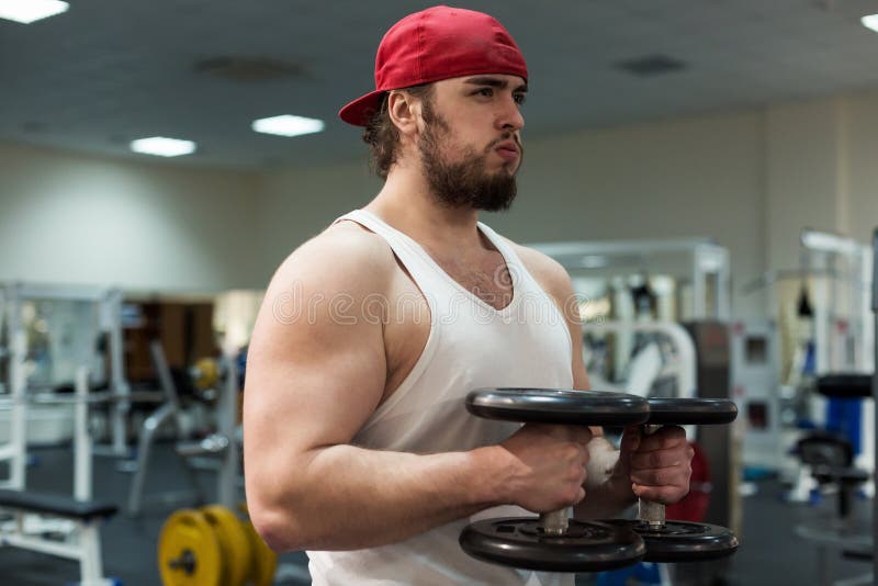 Sterke mens, bodybuilder die met domoren in een gymnastiek uitoefenen stock fotografie Sterke mens, bodybuilder die met domoren in een gymnastiek uitoefenen stock fotografie