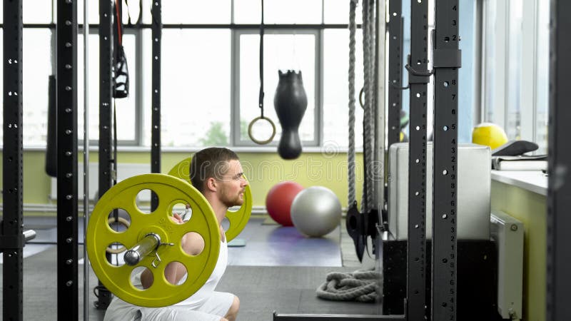 Sterkte opleiding in de gymnastiek kerel die hurkzit met een barbell doen bodybuilder die oefening met barbell doen Zachte nadruk royalty-vrije stock fotografie Sterkte opleiding in de gymnastiek kerel die hurkzit met een barbell doen bodybuilder die oefening met barbell doen Zachte nadruk royalty-vrije stock fotografie