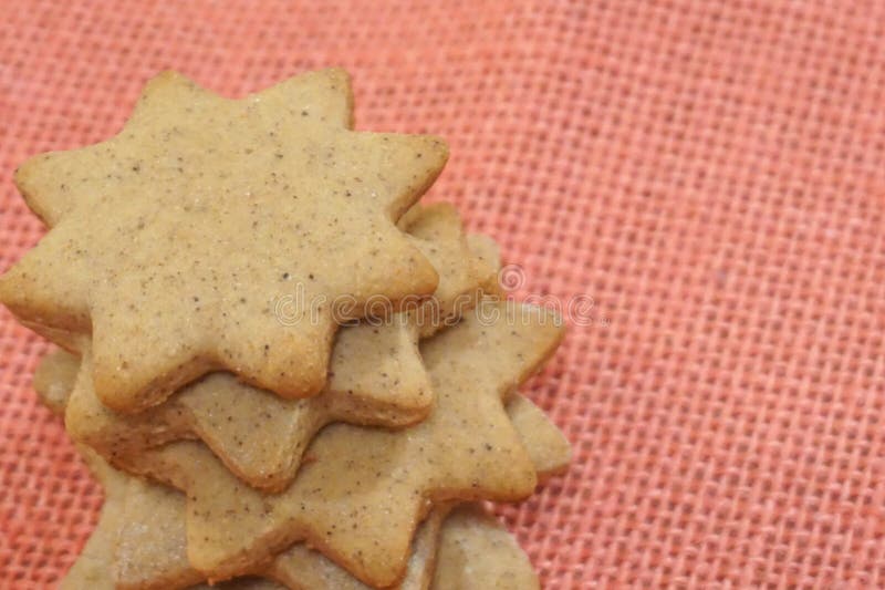 Sternförmige gewürzte Weihnachtsplätzchen auf rosa Jutefaserhintergrund stockfotografie Sternförmige gewürzte Weihnachtsplätzchen auf rosa Jutefaserhintergrund stockfotografie