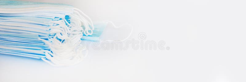 Pile of surgical medical disposable face masks  on panoramic white background with copy space, Covid-19 protection web banner. Pile of surgical medical disposable face masks  on panoramic white background with copy space, Covid-19 protection web banner