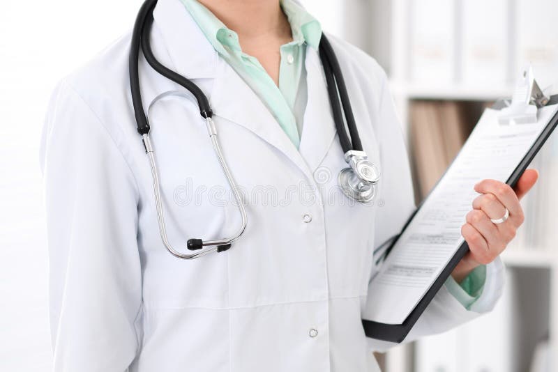 Stethoscope at female doctor breast at hospital office. Unknown physician`s hands close-up. Medicine and health care concept. Stethoscope at female doctor breast at hospital office. Unknown physician`s hands close-up. Medicine and health care concept.