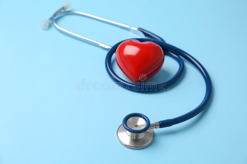 Stethoscope and heart model on color background