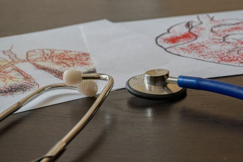 A stethoscope with medical illustrations of the respiratory and circulatory system on a table. A stethoscope with medical illustrations of the respiratory and circulatory system on a table