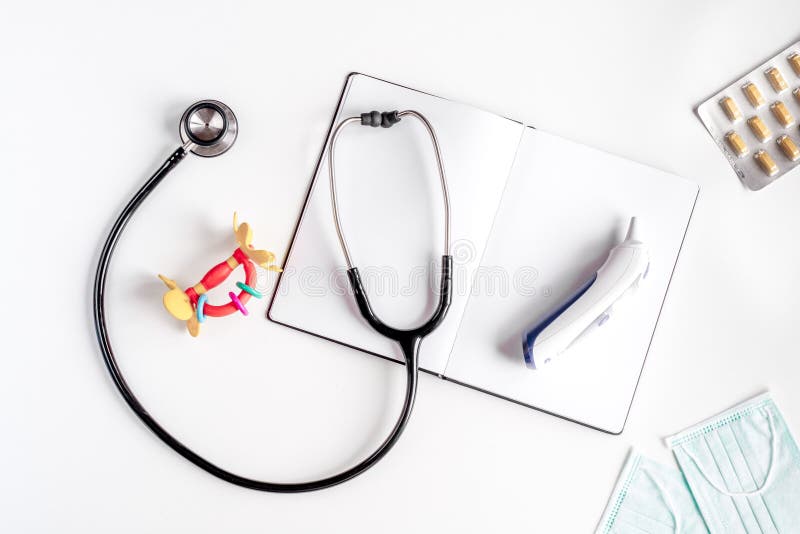 Stethoscope, notebook on children`s doctor office desk background top view mockup