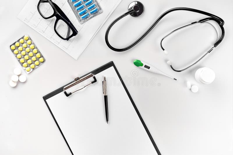 Stethoscope in the office of doctors.Top view of doctor`s desk table, blank paper on clipboard with pen. Copy space