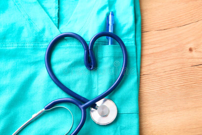 Stethoscope shaping heart and clipboard on medical uniform, closeup