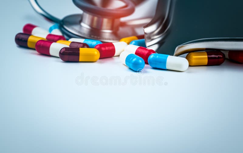 Stetoscopio con il mucchio delle pillole antibiotiche variopinte della capsula sulla tavola bianca con il vassoio della droga Far fotografie stock Stetoscopio con il mucchio delle pillole antibiotiche variopinte della capsula sulla tavola bianca con il vassoio della droga Far fotografie stock
