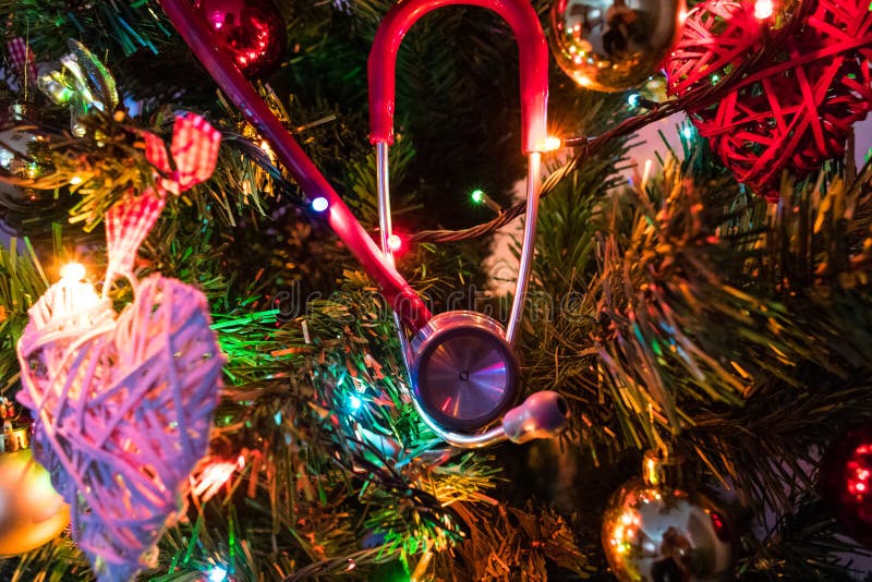 Stetoscopio rosso che appende su un albero di Natale decorato Natale medico immagini stock libere da diritti Stetoscopio rosso che appende su un albero di Natale decorato Natale medico immagini stock libere da diritti