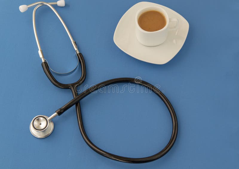 Stetoskop kopp kaffe på en blå bakgrund stetoskop f?r pengar f?r begreppsliesmedicin set arkivbild Stetoskop kopp kaffe på en blå bakgrund stetoskop f?r pengar f?r begreppsliesmedicin set arkivbild