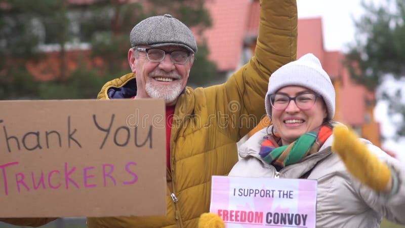 Steun voor antivaccinatieprotesten in canada in ottawa. een man en een vrouw in warme kleren houden borden met borden