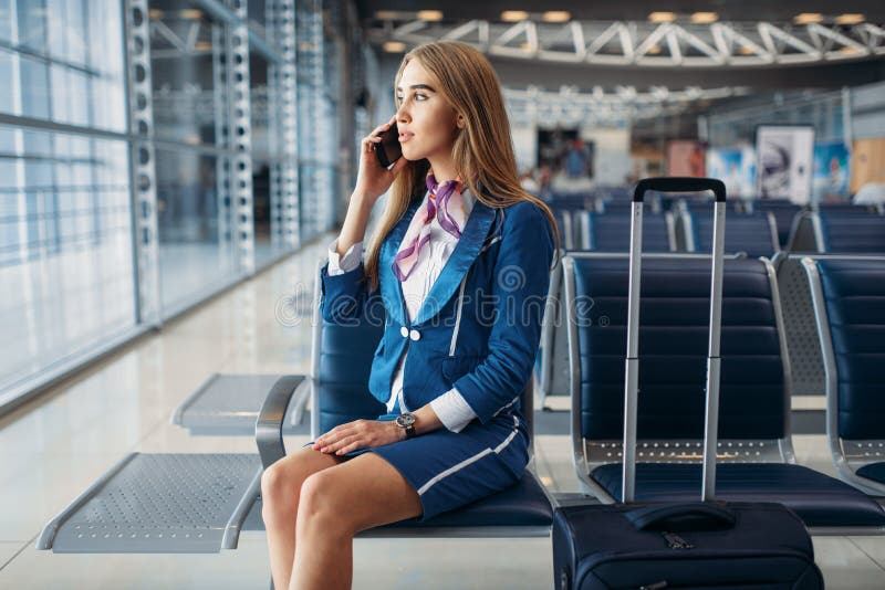 Stewardesa opowiada telefonem komórkowym w lotnisku