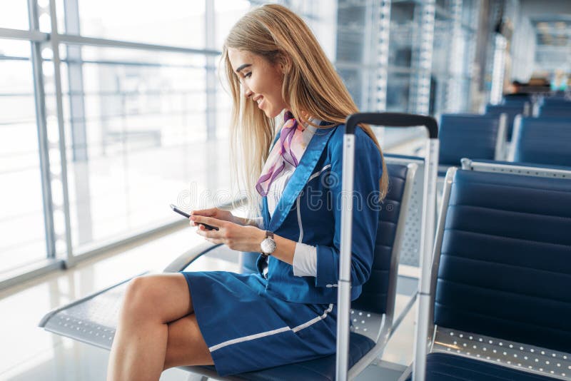 Stewardesa używa telefon w czekanie terenie w lotnisku