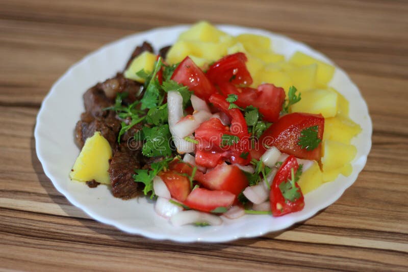 Stewed potatoes with fried beef, onions and red tomatoes with greens on a gravy stock images Stewed potatoes with fried beef, onions and red tomatoes with greens on a gravy stock images