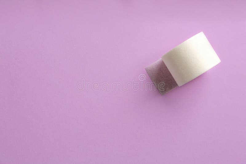 Sticking plaster roll on lilac background, top view. Space for text