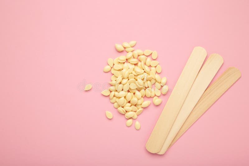 Sticks of Wood for Wax and Spa with Wax Granules on the Pink Background