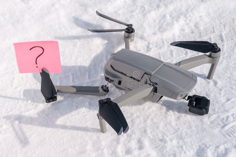 Sticky note with question mark in propeller blades of broken drone on snow stock photography