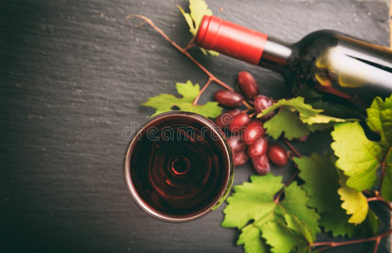 Sticla și sticla de vin roșu și strugurii proaspeți pe fond negru se concentrează asupra sticlei de vin royalty free stock image