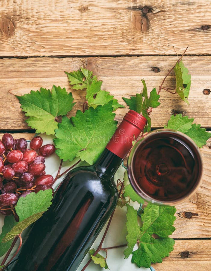 Sticlă și sticlă de vin roșu și struguri proaspeți pe fond de lemn stock photos