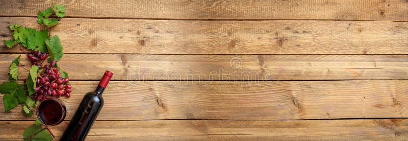 Sticlă și sticlă de vin roșu și struguri proaspeți pe fond de lemn stock image