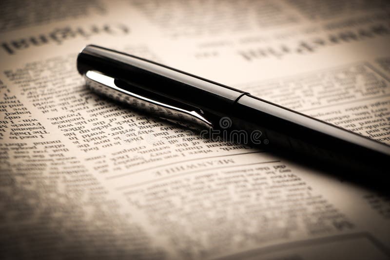 Black pen is lying on the newspaper. Black pen is lying on the newspaper.