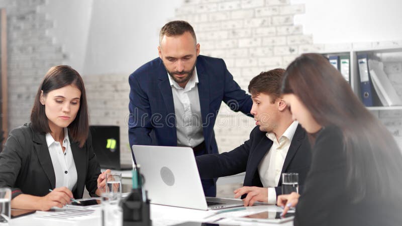 Stijlvolle zakenmensen die een pak dragen terwijl ze praten met mannelijke teamleider en teammeeting hebben op kantoor