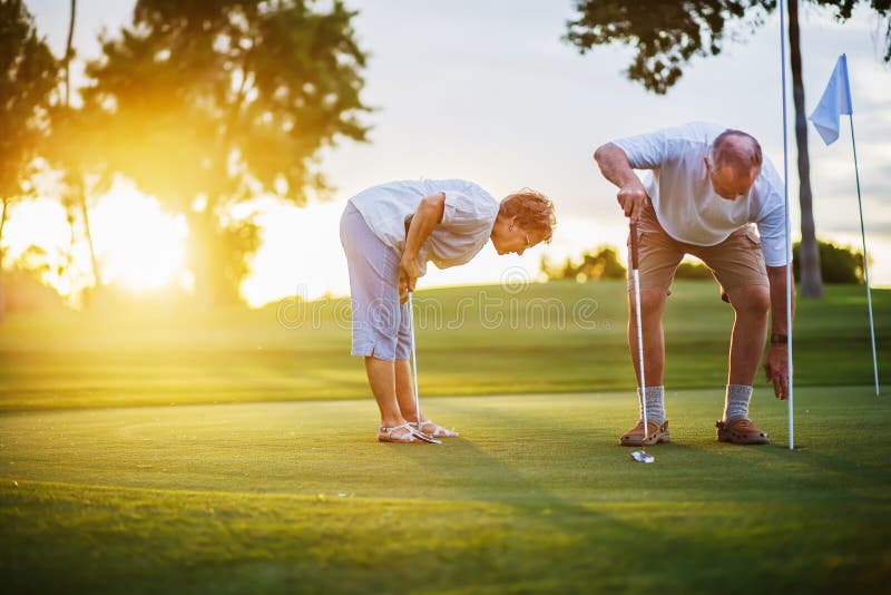 Stile di vita senior attivo, coppia anziana che gioca insieme golf al tramonto immagine stock Stile di vita senior attivo, coppia anziana che gioca insieme golf al tramonto immagine stock