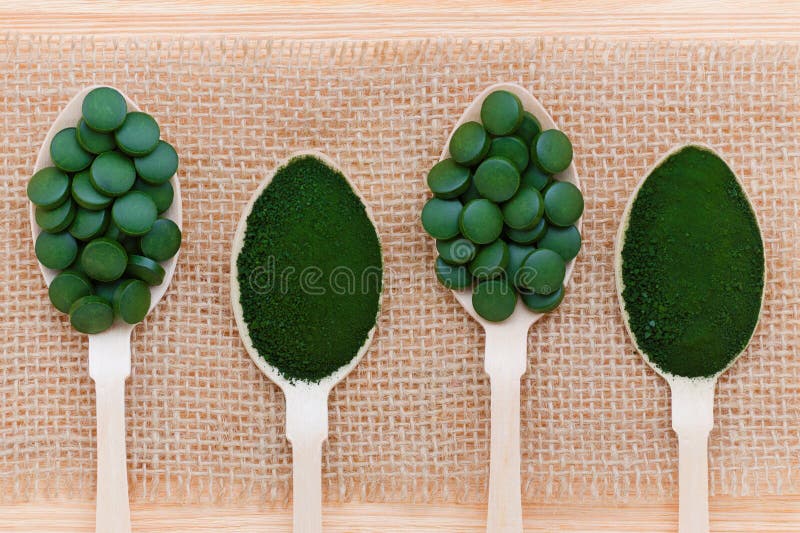 Stile di vita, superfood, alga, spirulina e pillole e polvere sani della clorella in cucchiai di legno fotografie stock Stile di vita, superfood, alga, spirulina e pillole e polvere sani della clorella in cucchiai di legno fotografie stock